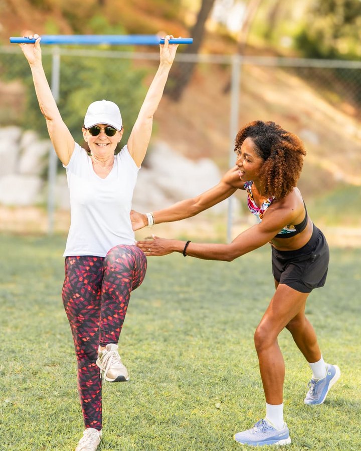 Aurélie Kamga, coach sportif à Montferrier-sur-Lez, guide une adhérente sur un exercice de mobilité avec barre, en extérieur